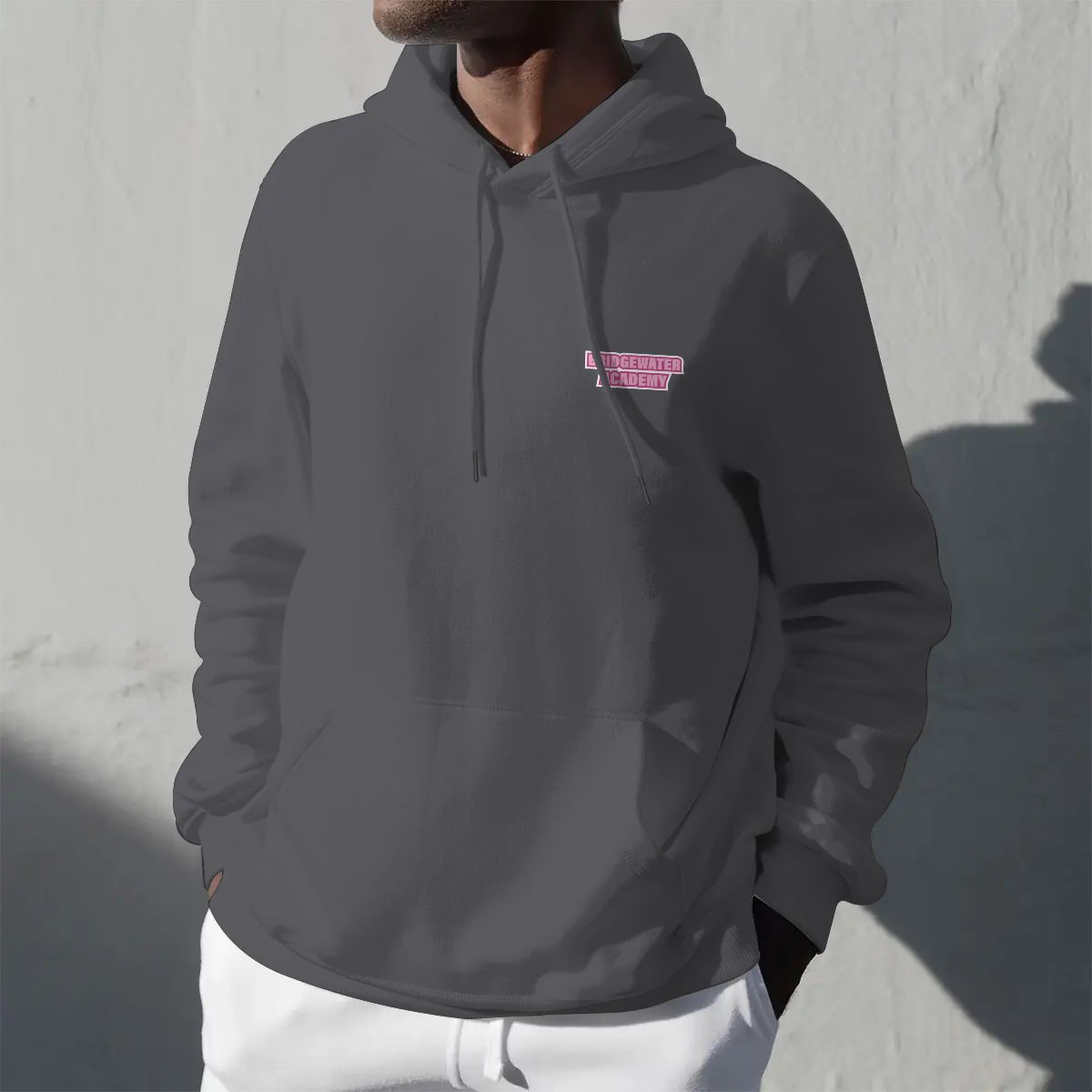 Person wearing a dark gray hoodie with a logo on a light gray background
